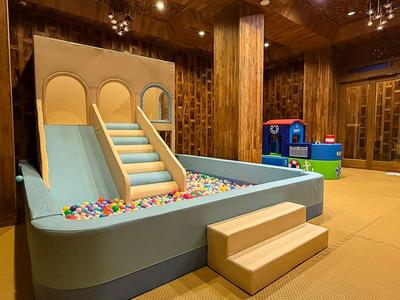 Children's play area with slide and ball pit in a wood-paneled room.