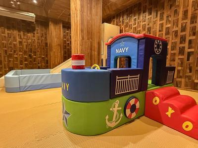 Colorful children's play area with climbing structure and slide in a room with wood paneling.