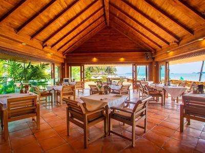 Open restaurant with wooden roof and view of a beach and the sea.