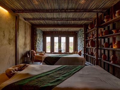 Gemütliches Hotelzimmer mit zwei Betten, natürlich beleuchtet und mit dekorativen Elementen aus Holz.