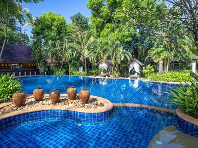 Blauer Pool in tropischer Gartenanlage mit grünen Bäumen, Töpfen und weißer Statue.