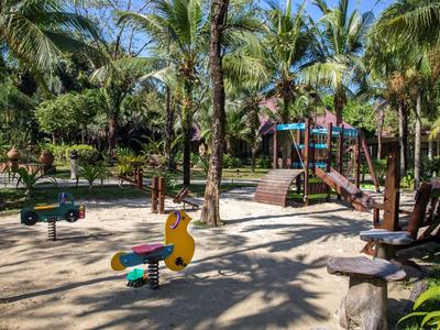 Spielplatz mit bunten Spielgeräten und Palmen an einem sonnigen Tag