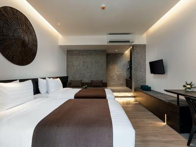 Modernes Hotelzimmer mit zwei Betten, braunen Decken und grauer Akzentwand.