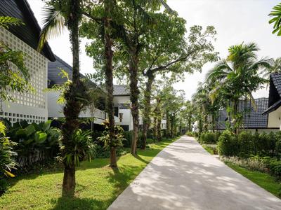Ein heller Gehweg mit Palmen und weiß gestrichenen Gebäuden auf beiden Seiten unter blauem Himmel.