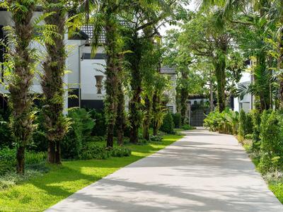 Weg durch grünen Garten mit Bäumen zu einem Eingang in einem Hotel.