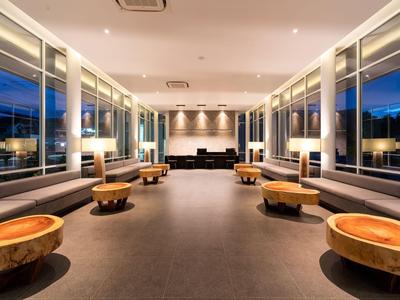 Moderner Lounge-Bereich mit runden Holztischen und großen Fenstern bei Dämmerung.