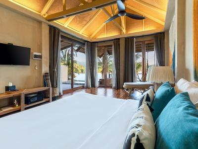 Modernes Hotelzimmer mit großen Fensterfronten und Blick auf tropischen Garten.