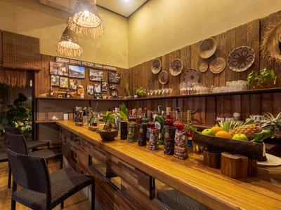 Gemütliche Hotelbar mit Holztisch, Stühlen und Dekoration aus Körben und Pflanzen.