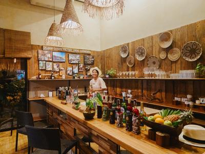 Innenraum einer rustikalen Hotelbar mit Holztisch, Flaschen und dekorativen Wandkörben.
