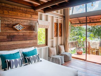 Gemütliches Hotelzimmer mit Holzverkleidung, stilvollem Bett und Blick auf eine Terrasse mit Aussicht.