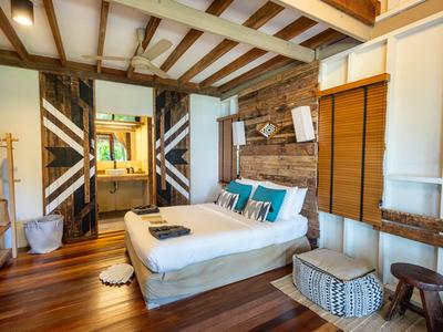 Modernes Hotelzimmer mit Holzbalkendecke, Doppelbett und rustikalen Holzwänden.