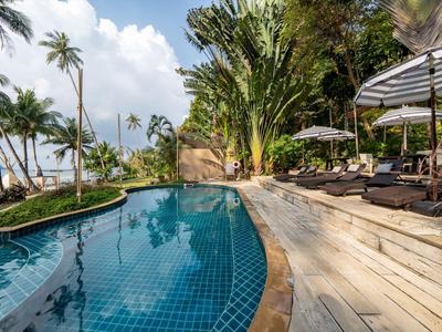 Luxuriöser Poolbereich mit Liegen und Palmen, ideal für einen entspannenden Urlaub am Meer.