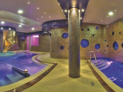 Area interna di un hotel con piscina e zona benessere, illuminata dolcemente da luci ambientali.