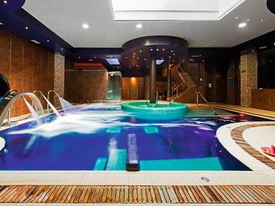 Piscina coperta con cascate, vasca idromassaggio e interno bagno di lusso in un hotel.