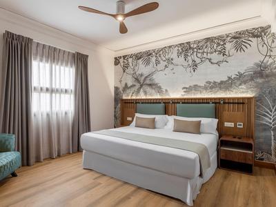 Habitación de hotel moderna con cama grande, decoración gris en la pared y suelo de madera.