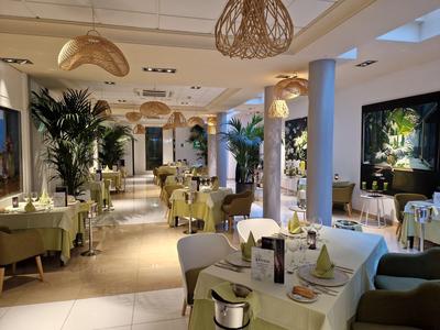 Restaurant élégant avec tables dressées, plantes et éclairage chaud pour un séjour à l'hôtel détendu.