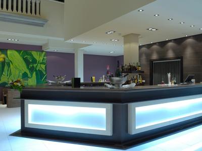 Area bar dell'hotel moderna con bancone illuminato e arredamento elegante.