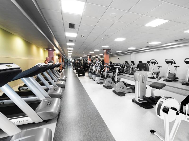 Palestra moderna con tapis roulant e attrezzi in una stanza luminosa e spaziosa.