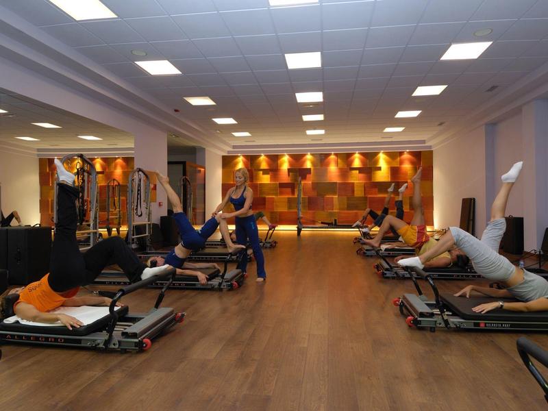 Sala fitness dell'hotel con diverse persone che si allenano su reformer Pilates.