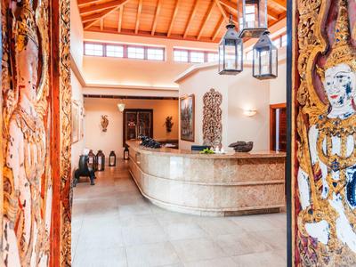 Ingresso d'hotel luminoso con porte decorate artisticamente e reception in marmo.