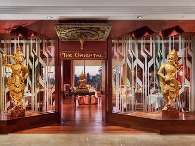 Eingang zu einem Restaurant mit zwei großen goldfarbenen Statuen und traditioneller asiatischer Dekoration.