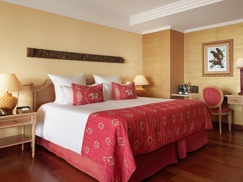 Stanza d'albergo elegante con letto grande, coperta rossa e mobili in legno.
