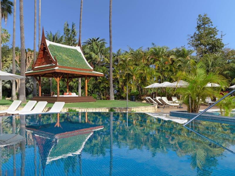 Piscina di lusso con lettini e padiglione ombreggiato in un resort tropicale.