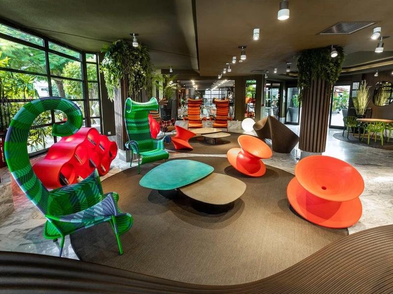 Modern hotel lobby with colorful, unique seating and large windows overlooking greenery.