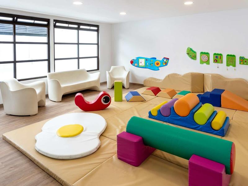 Bright play area with colorful soft seating and play furniture in a modern room.