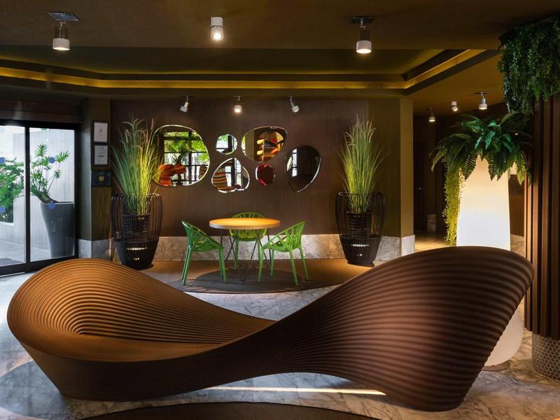 Modern hotel lobby area with curved brown seating and plants.