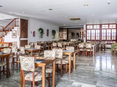 Großer, heller Speisesaal mit Holztischen, gepolsterten Stühlen und Marmorboden.