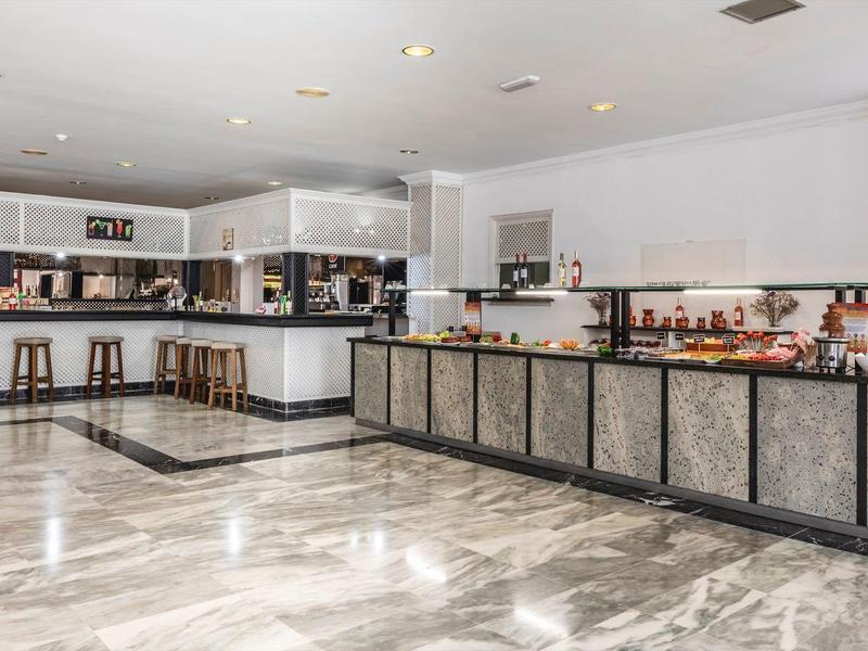 Buffet per la colazione moderno in una luminosa sala ristorante dell'hotel con pavimento in marmo e sgabelli da bar.