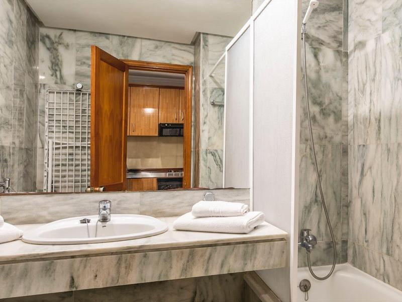 Bagno con pareti in marmo, doppio lavandino, vasca da bagno e asciugamani sul bancone.