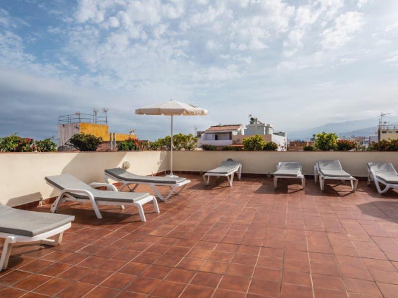 Lettini vuoti e un ombrellone su una terrazza con vista sul mare.