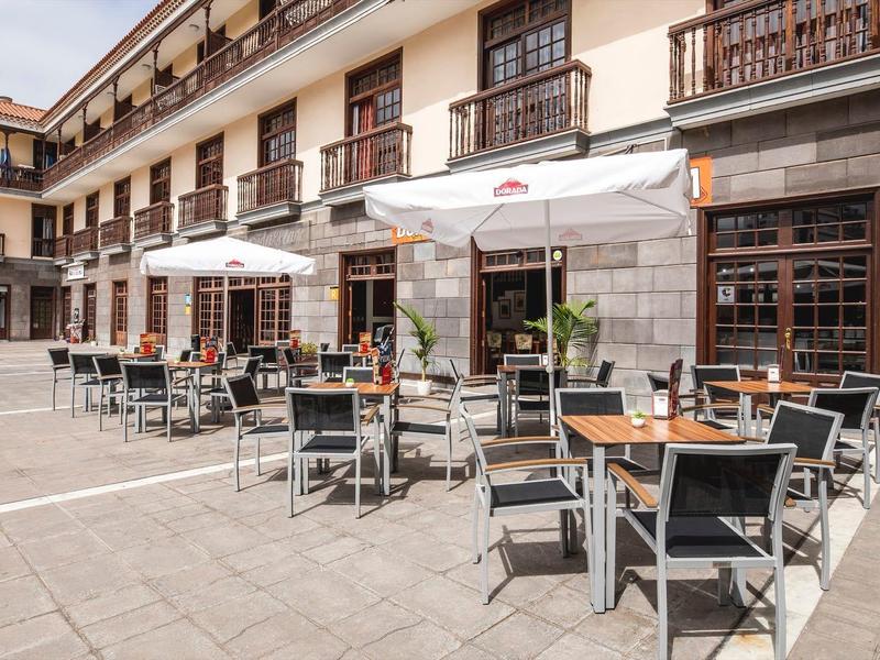 Cortile dell'hotel con area terrazza e tavoli sotto ombrelloni.