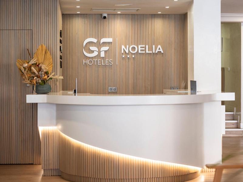 Accogliente reception di un hotel moderno con bancone bianco illuminato e rivestimento in legno.