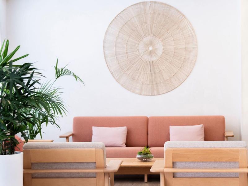 Area soggiorno moderna con divano, poltrone e pianta in tonalità neutre.