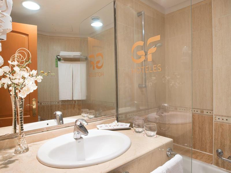 Bagno pulito con lavabo, specchio, asciugamani e vasca da bagno con doccia.