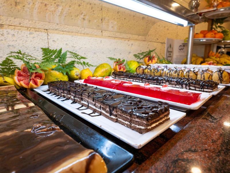 Vari dessert su piatti bianchi in un buffet con decorazioni di frutta.
