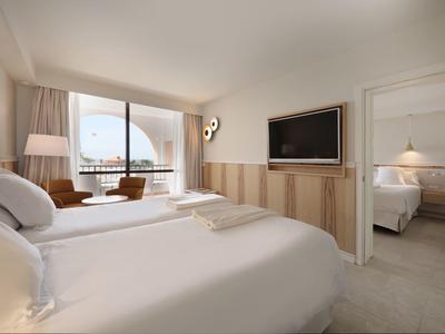 Modern eingerichtetes Schlafzimmer mit Doppelbett, Fernseher und Zugang zum angrenzenden Zimmer.