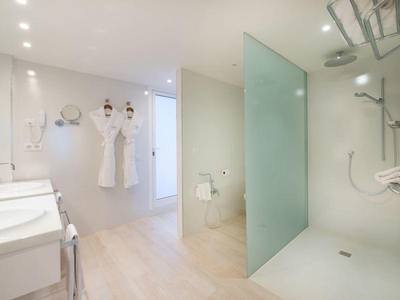 Helles Badezimmer mit großer Dusche, frosted Glaswand, zwei Bademänteln und modernen Armaturen.