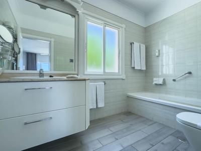 Modern bathroom with large bathtub, white vanity, and frosted window.