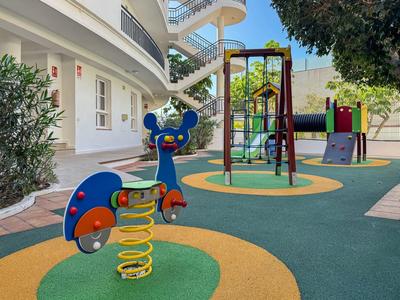 Colorful children's playground with spring rocker and climbing frame in front of a white building.