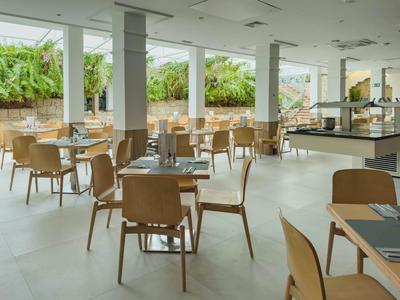 Bright restaurant with wooden tables and chairs, large windows, and a buffet area