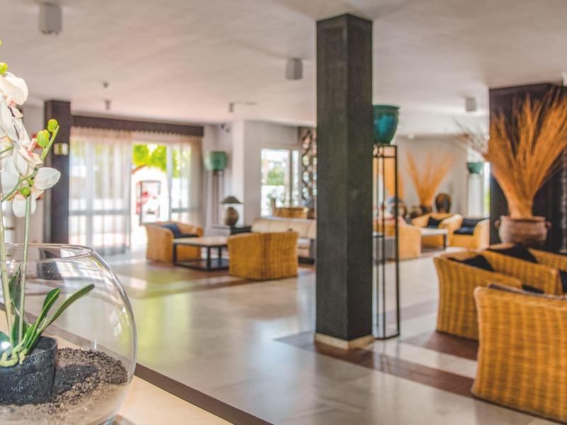 Modern hotel lounge area with wicker furniture, decor, and plenty of natural light.