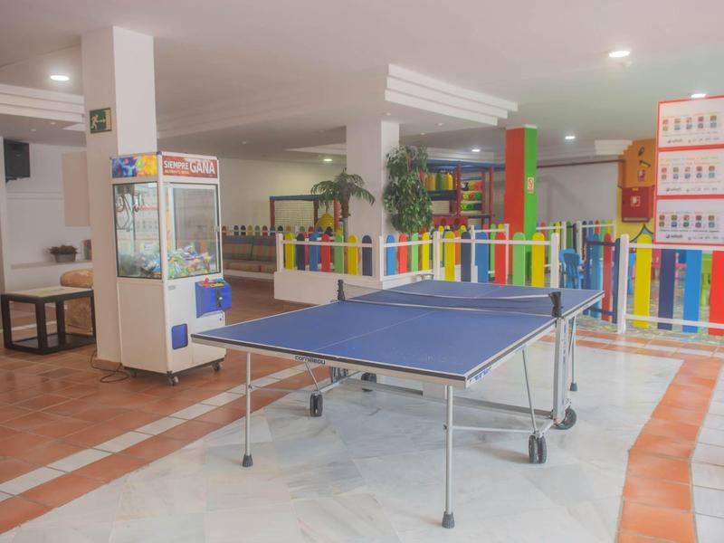Interior room with a blue ping pong table and a colorful play area in the background.
