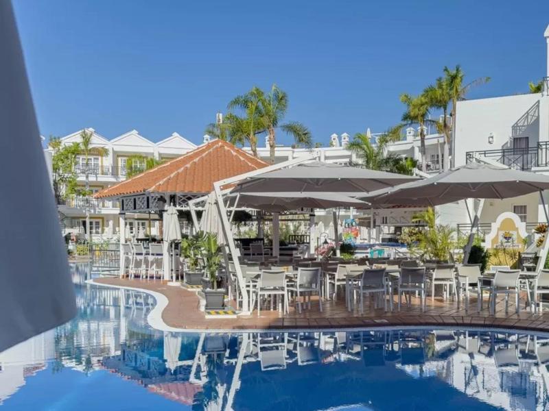 Modern hotel with pool and covered outdoor restaurant under clear sky