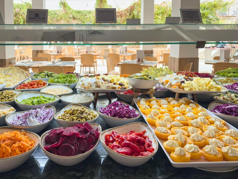 Varied buffet with fresh vegetables and salads in a bright, modern setting.