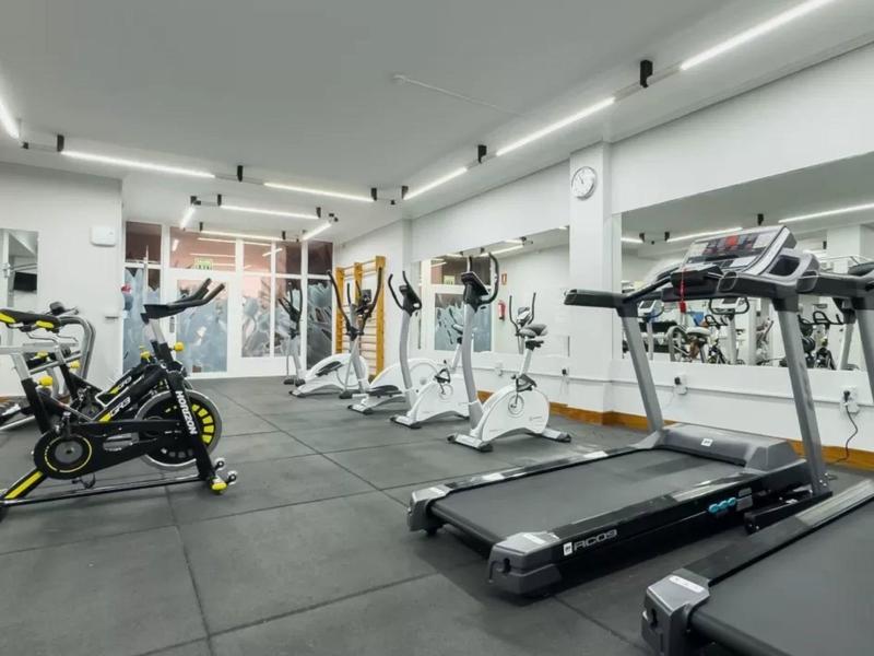 Modern gym with treadmills, spin bikes, and exercise equipment in a bright room.