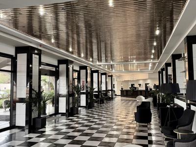 Großer Hotellobby-Bereich mit schwarz-weiß kariertem Boden und moderner Einrichtung.
